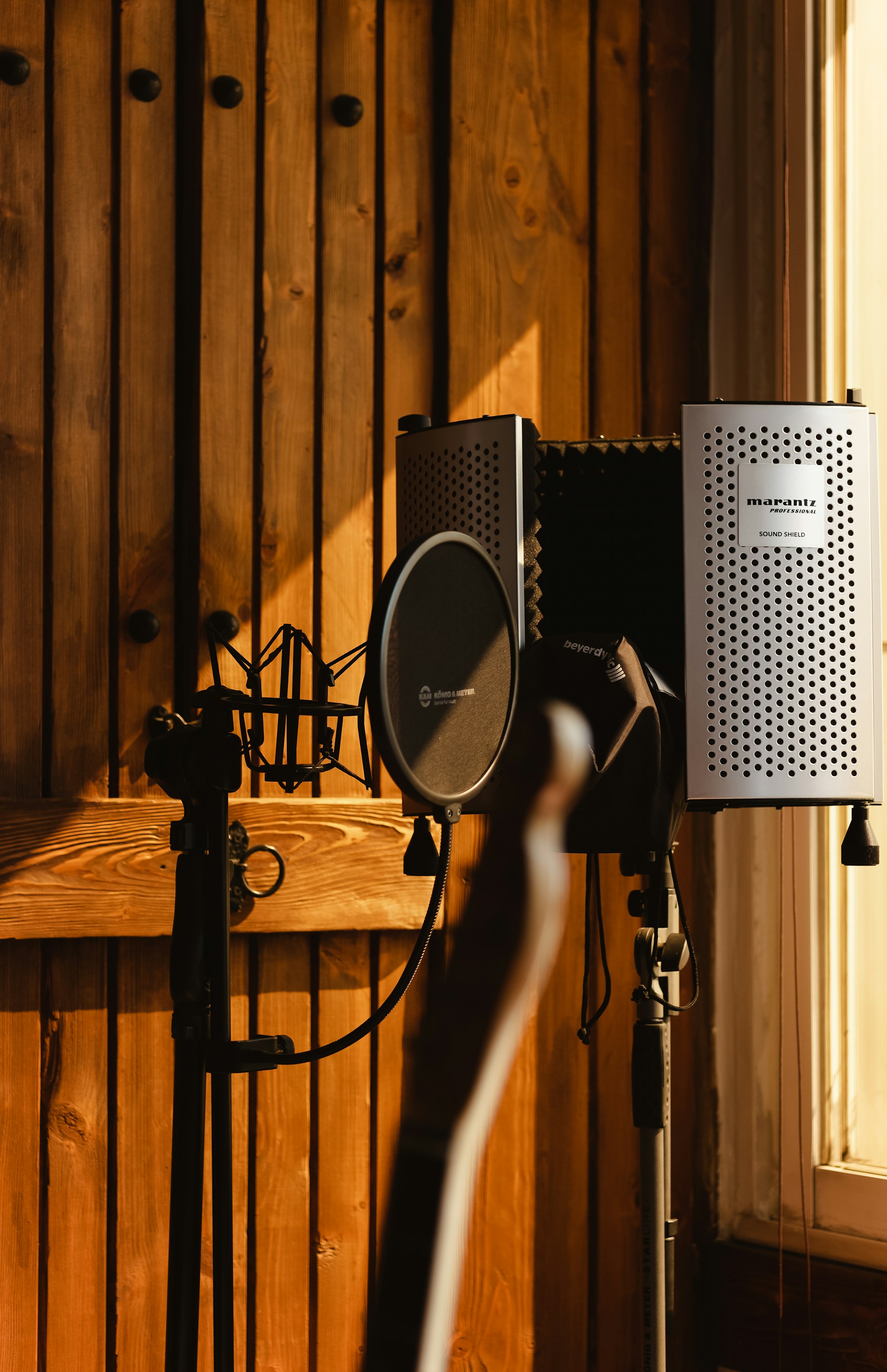 A studio microphone in a wooden recording booth, ready for a conversation